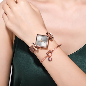 Détail d'une montre carrée or rose avec bracelet milanais et bracelet à nœud au poignet