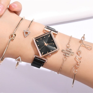 Détail de montre maille or rose avec cadran noir et quatre bracelets assortis