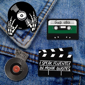 Detailed view of vintage music enamel pins on denim including vinyl and movie clapboard