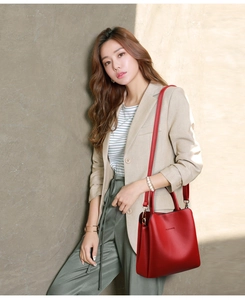 Detailed view of red leather bucket bag with metal hardware on model's shoulder