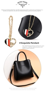Detail of heart-shaped gold charm with pearls and enamel on black bucket bag