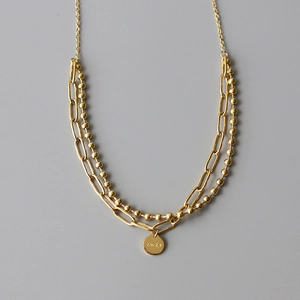 Detail of 18K gold plated double layer necklace featuring Lucky engraved round pendant