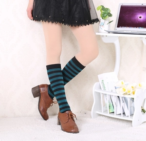 Close-up of black and dark green striped cotton knee socks styled with brown leather shoes