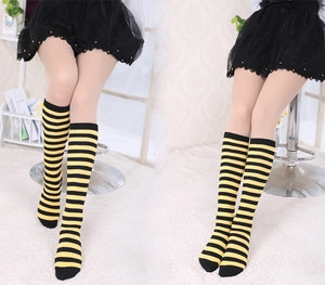 Detail of knee-high striped socks with yellow and black patterns on a model indoors