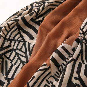 Macro shot of geometric caramel scarf showing smooth silk-like texture and draped fabric
