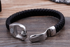 Detailed close-up of a black braided leather bracelet with a magnetic skull metal clasp