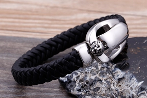 Macro detail of men's braided leather bracelet featuring a silver lion head metal clasp