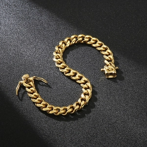 Detail of a chunky gold Cuban link chain bracelet with a secure box clasp on a black background