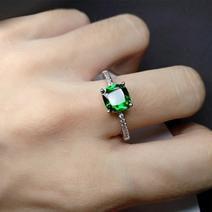 Classic silver ring with a square green gemstone and side diamonds on female hand