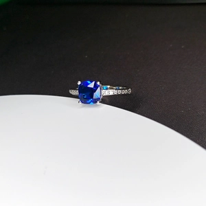 Detailed close-up of a silver ring featuring a blue square-cut gemstone and side diamonds