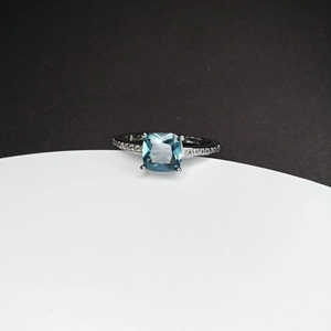 Macro detail of square blue gemstone ring with pave diamonds on silver band