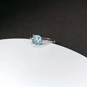 Macro side view of cushion cut light blue gemstone ring with pave set side diamonds