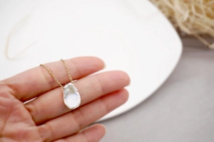Macro shot of an irregular white baroque pearl pendant on a delicate gold chain link