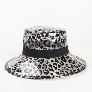 Détail du chapeau bob en PVC léopard montrant la texture brillante et le ruban noir
