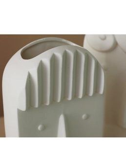 Detailed macro shot of white matte ceramic face vase showing abstract artistic texture