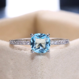 Macro shot of cushion cut light blue zircon gemstone set in a pavé silver ring band