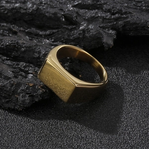 Polished gold square signet ring for men on a dark volcanic rock background