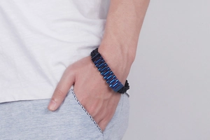 Detail of blue metal clasps and black woven cord on a trendy men's steel bracelet