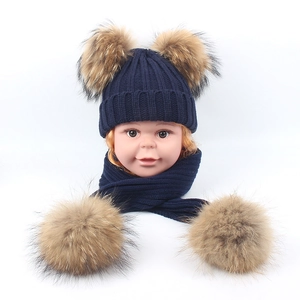 Detail of dark blue knit hat and scarf set with four large natural raccoon fur pom-poms