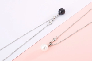 Macro detail of stainless steel necklace with heart charm and pearl shell pendants