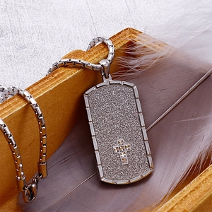 Silver military tag necklace with cross pattern inside a wooden box with feather decor