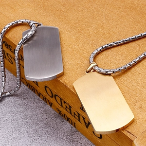 Detailed view of silver and gold dog tag necklaces with chains on a wooden surface