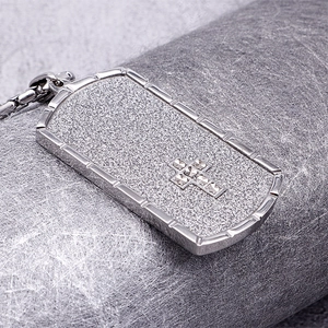 Macro shot of silver rectangular military pendant with cross inlay on matte steel