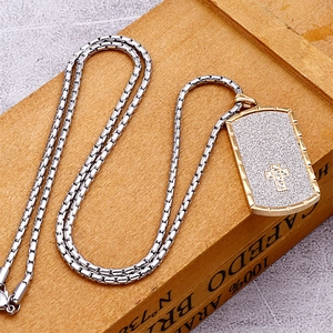 Minimalist silver chain necklace with a frosted gold cross pendant on a wooden background