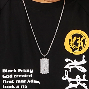 Close-up of silver military tag necklace with cross relief on a black t-shirt