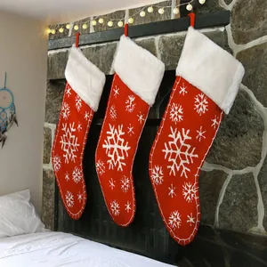 Detailansicht roter Strick-Weihnachtssocken mit weißen Schneeflocken am Kamin