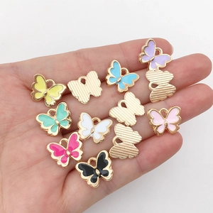 Colorful butterfly enamel charms in gold metal displayed on a hand for DIY jewelry making