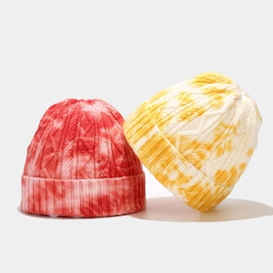 Detail of red and yellow tie-dye knitted beanies featuring thick cable knit texture