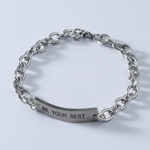 Macro detail of silver stainless steel curb chain bracelet with engraved BE YOUR BEST plate