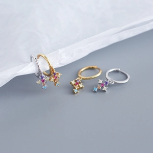 Macro detail of cross earrings featuring colorful cubic zirconia on gold and silver bands