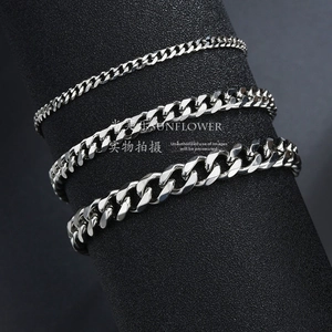 Detailed view of silver Cuban link chains in three different widths on a black display stand
