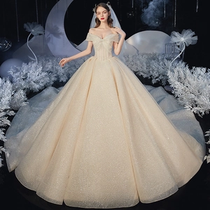 Champagne starry off-shoulder wedding gown with sequins and long train in dreamlike setting