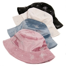 Detail view of plush bucket hats with butterfly embroidery in pink blue beige and black