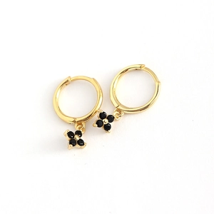 Elegant gold hoop earrings with black quatrefoil flower charms in a minimalist luxury style