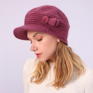 Detailaufnahme der Strickmütze mit Schirm, Schleife und Bommel in Dunkelrosa