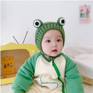 Detailed knit texture of green frog-themed baby romper and matching crochet hat