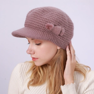 Detailansicht der Strickstruktur mit Schleife und Pelzball an der mauvefarbenen Mütze