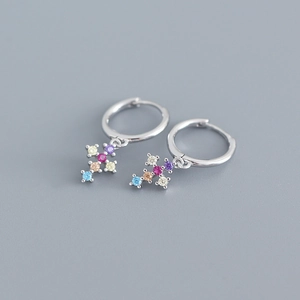 Close-up of silver earrings with cross pendants and colorful zircon stones