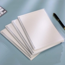Detailed view of four spiral bound notebooks with lined pages on a blue desk