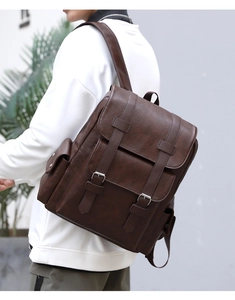 Detailed view of dark brown PU leather backpack with buckle straps worn by a model