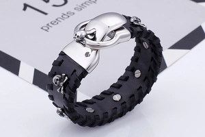 Close-up detail view of a punk men's wide black leather bracelet with silver skull rivets