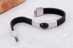 Detail of black leather bracelet with silver steel plate and centered black gemstone