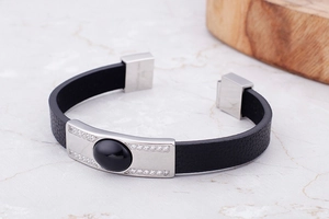 Macro shot of men's black leather bracelet with crystal-inlaid silver plate and oval stone