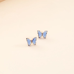 Close-up of golden butterfly earrings with blue translucent wings and white zircon detail