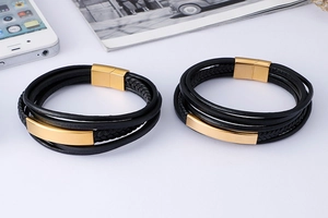 Detail of multi-layer woven black leather bracelet with gold magnetic clasp on white background