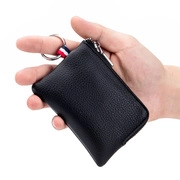 Detail of hand holding a black litchi grain leather key pouch with metal zip and keyring